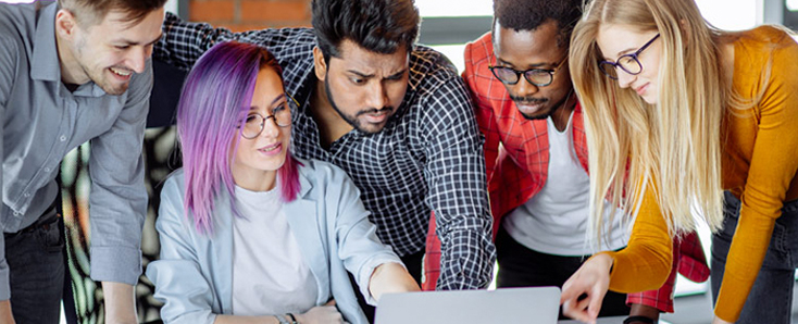 picture of four students looking at a laptop computer