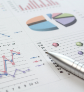 pen on top of a page with graphs and charts.