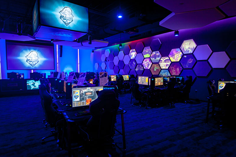 Room filled with tables and monitors. One wall has a large projection screen.