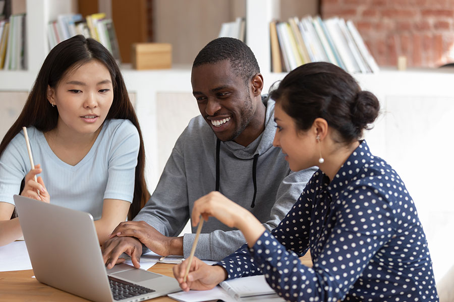 Three students looking at a laptop